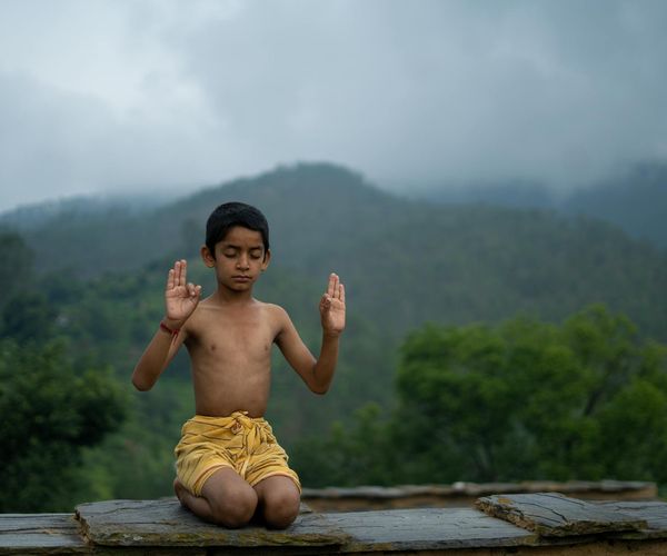 Person meditating peacefully outdoors with a serene natural background.