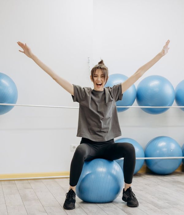 Woman performing a gentle stretching exercise in a brightly lit room.